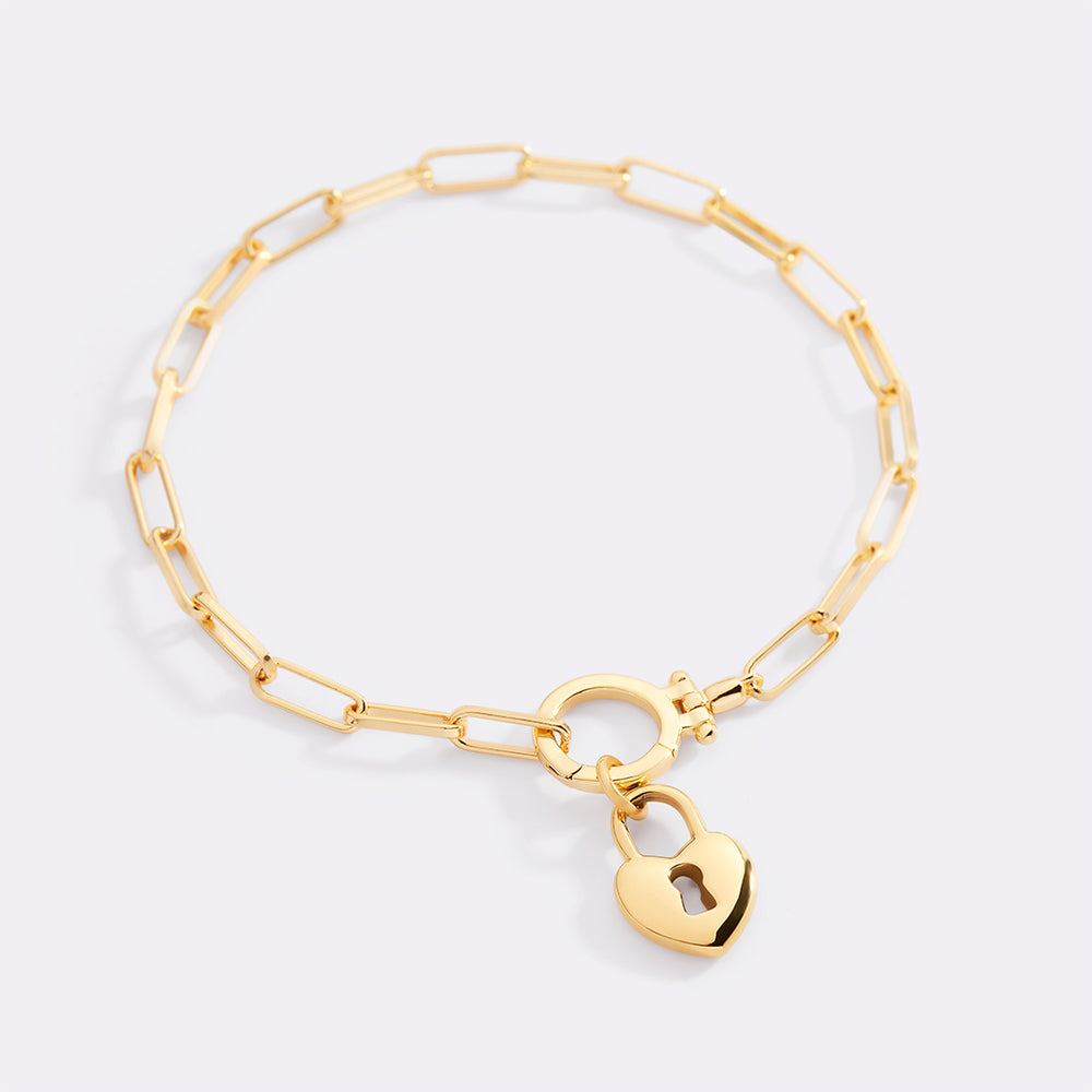 Gold bracelet with a heart-shaped padlock charm on a light gray background
