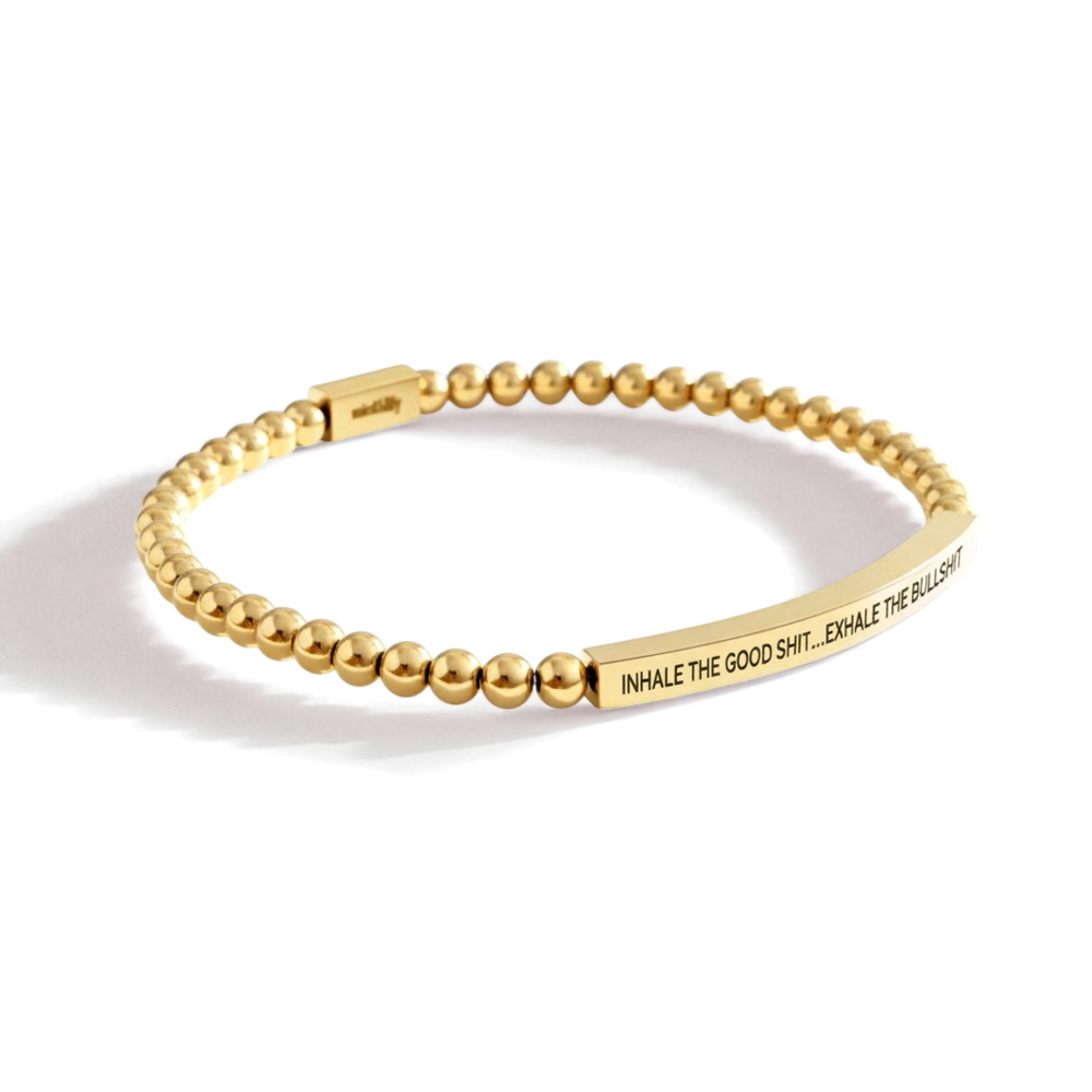 Gold beaded bracelet with motivational quote on a white background