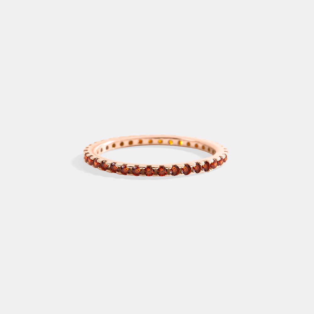 Rose gold ring with small gemstones on a light gray background