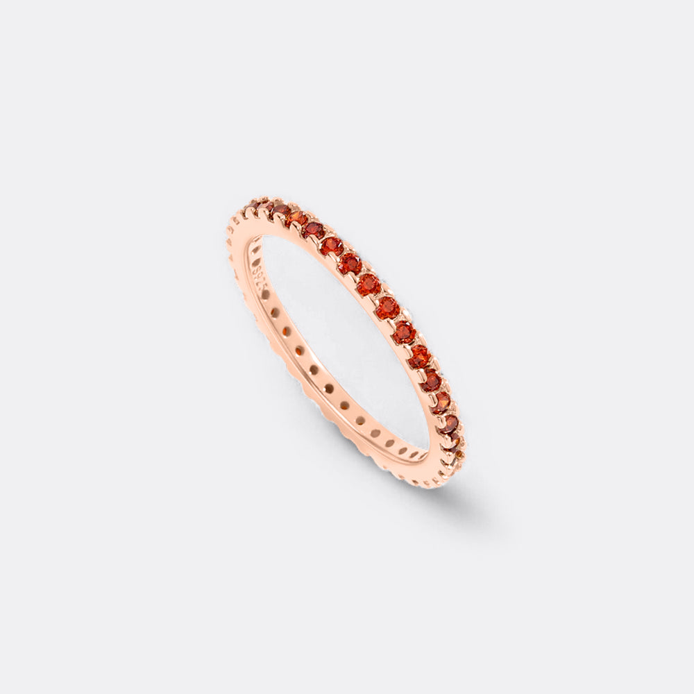 Rose gold ring with small red stones on a light gray background