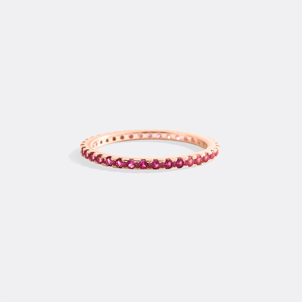 Rose gold ring with red gemstones on a light gray background