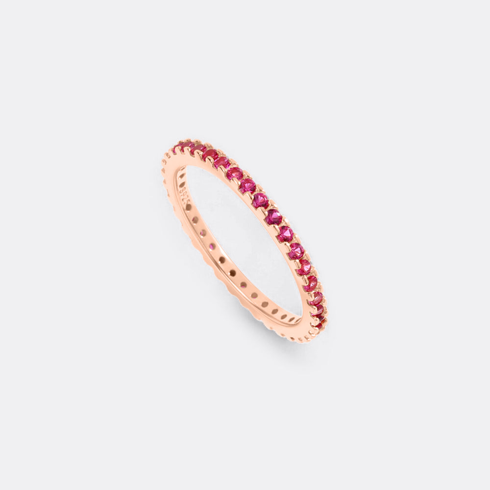 Rose gold ring with red gemstones on a light gray background