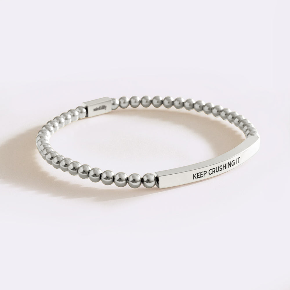 Silver beaded bracelet with engraved message on a white background