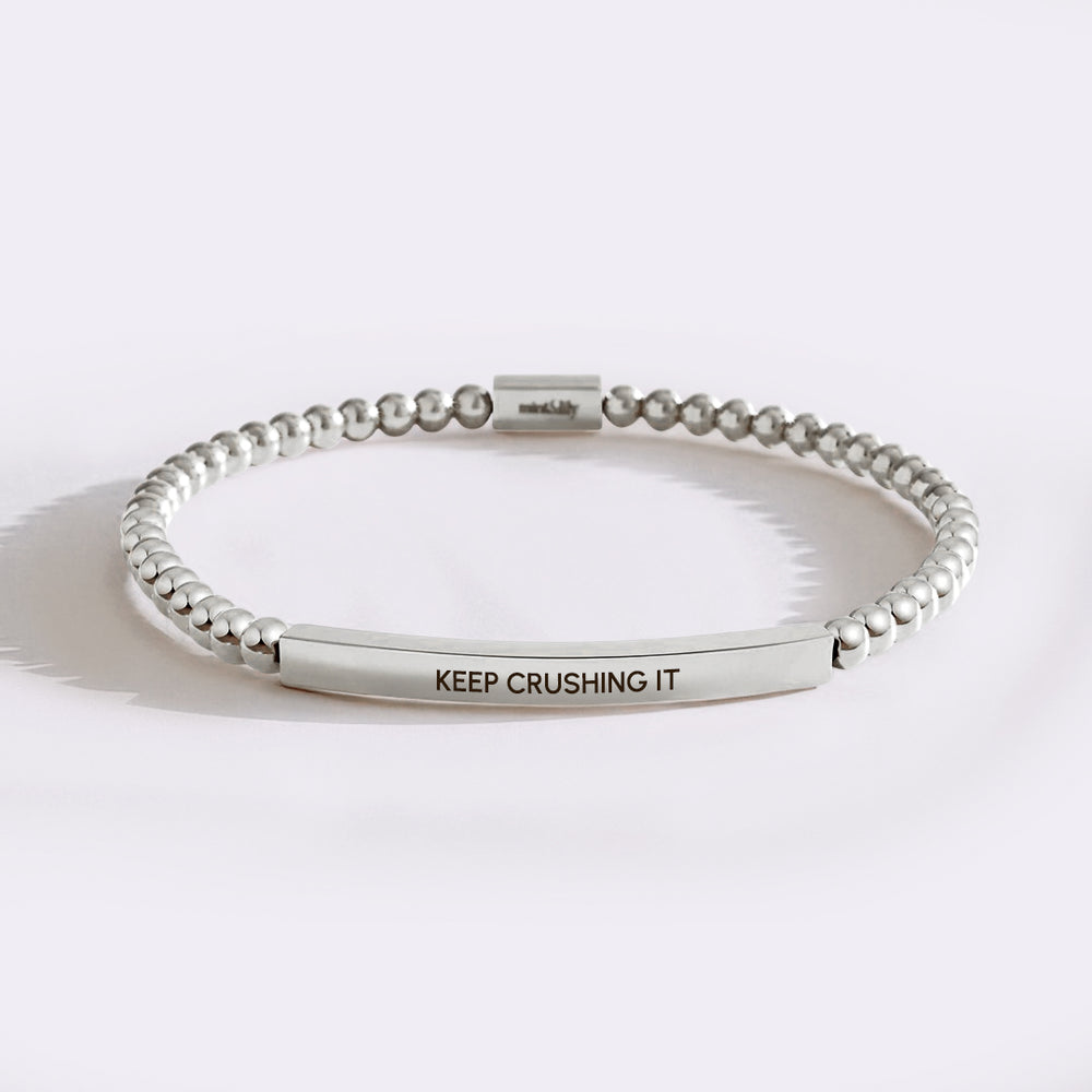 Silver beaded bracelet with 'KEEP CRUSHING IT' engraving on a white background