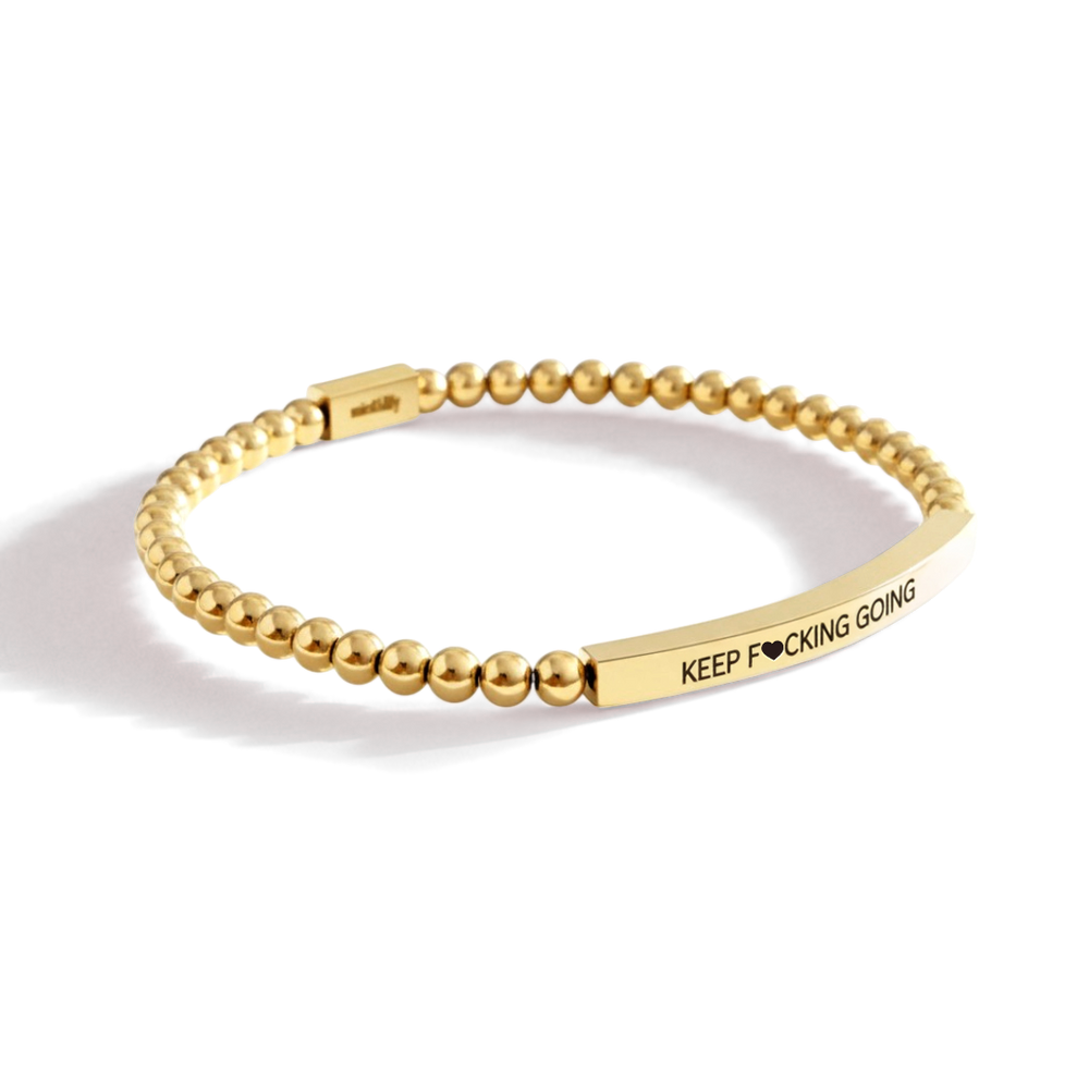 Gold beaded bracelet with a motivational message on a white background
