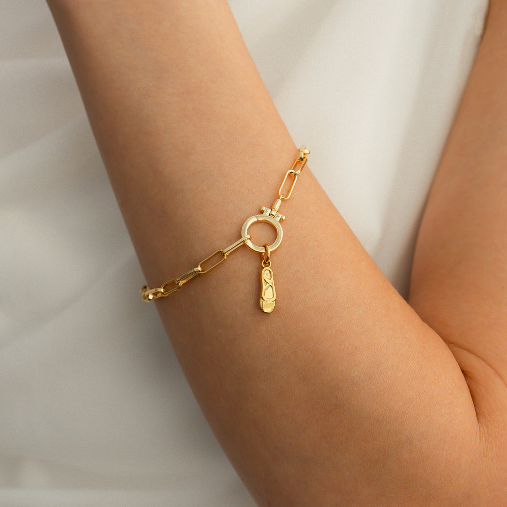 Gold bracelet with a unique charm on a person's wrist against a white background