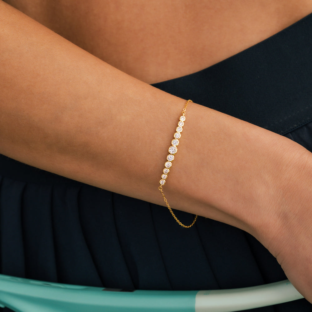 Gold bracelet with pearls on a person's wrist against a dark background