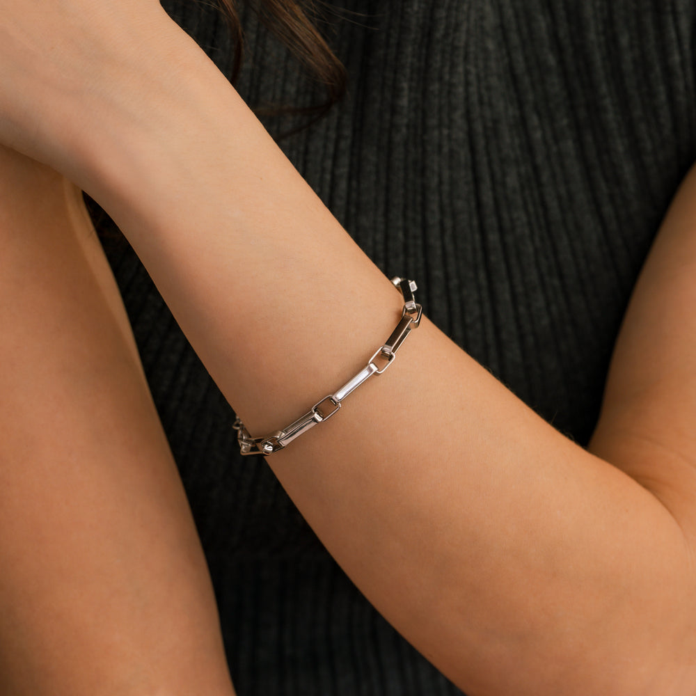 Silver bracelet on a person's wrist with a neutral background