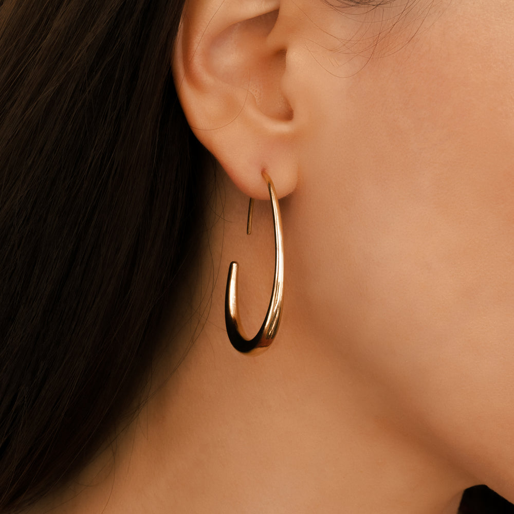 Gold hoop earring worn by a person with dark hair.