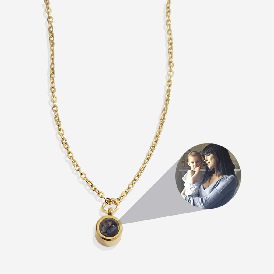 A gold necklace with a small photo inside the middle of the charm