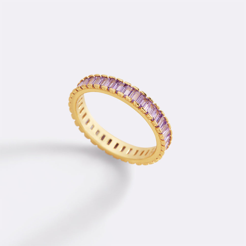 Gold ring with pink gemstones on a light gray background