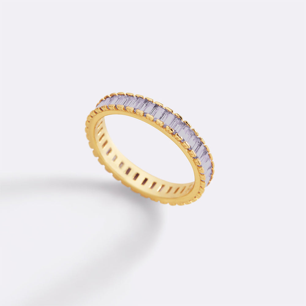 Gold ring with baguette-cut diamonds on a light gray background