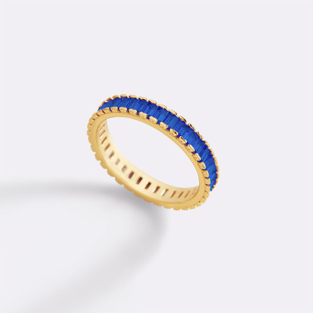 Gold ring with blue gemstones on a light gray background