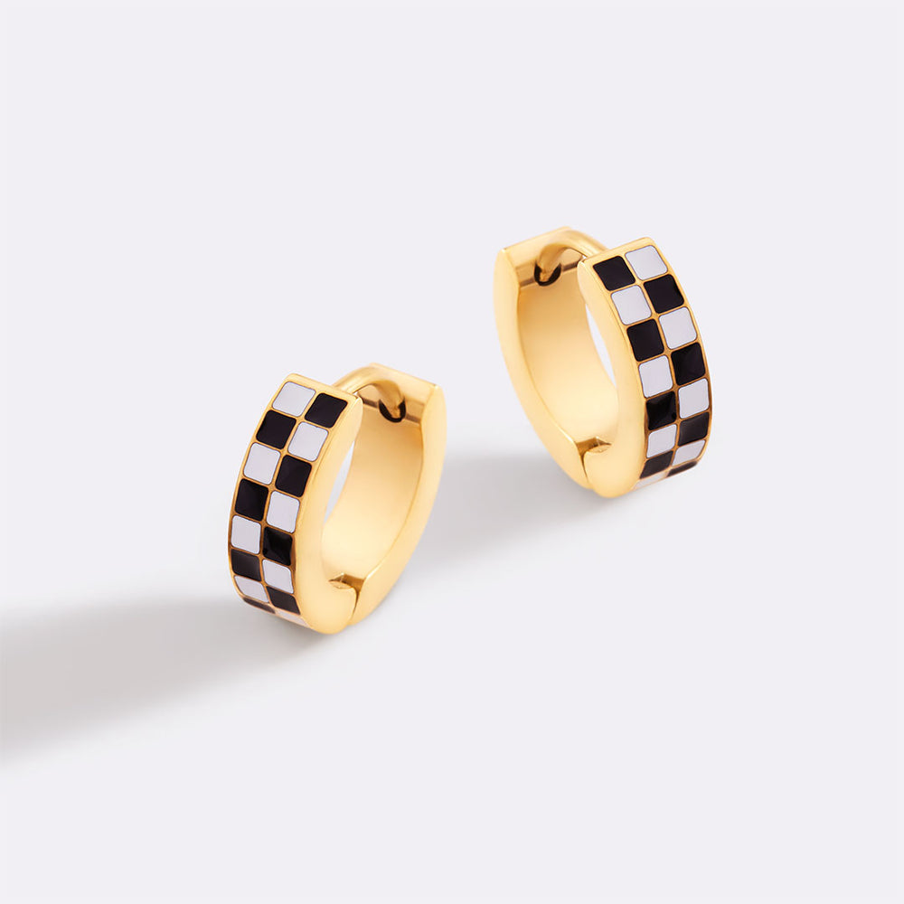 Gold hoop earrings with black and white checkered pattern on a light gray background