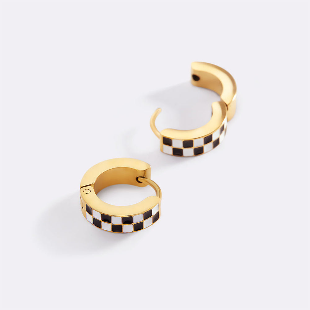 Gold hoop earrings with black and white checkered pattern on a light gray background