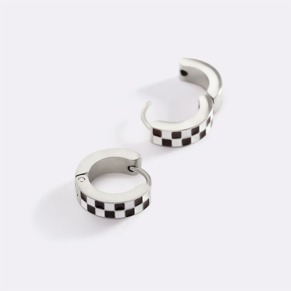 Pair of silver hoop earrings with black and white checkered pattern on a white background