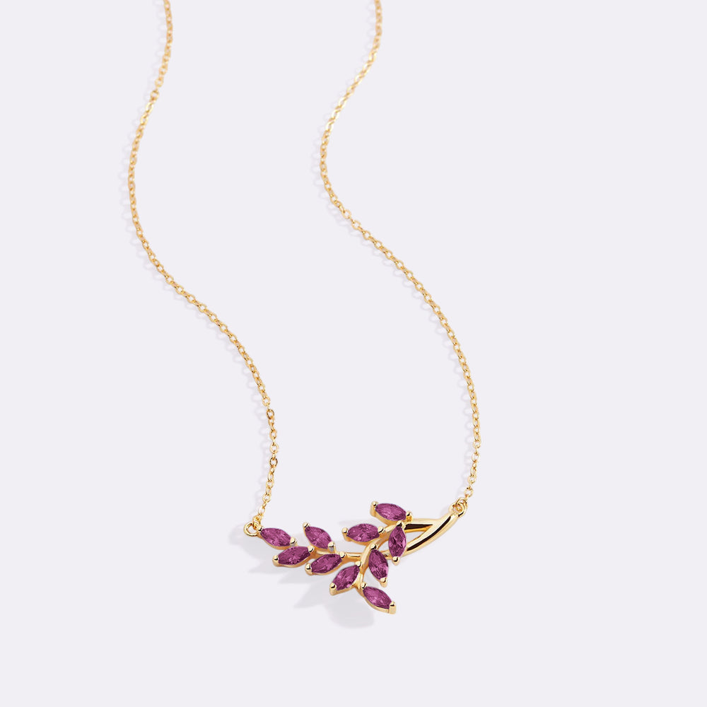 Gold necklace with purple gemstones on a light gray background