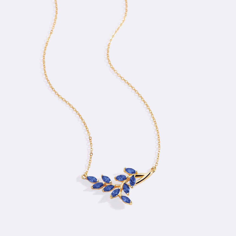 Gold necklace with blue gemstones on a light gray background