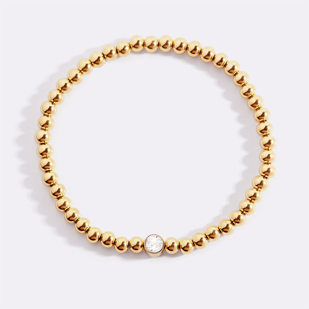 Gold beaded bracelet on a light background