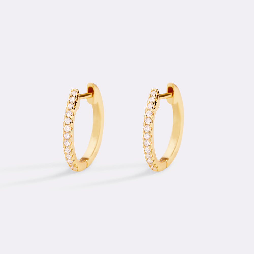 Gold hoop earrings with small diamonds on a light gray background