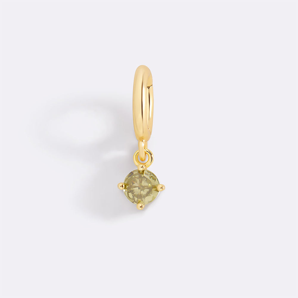 Gold earring with a green gemstone on a light gray background