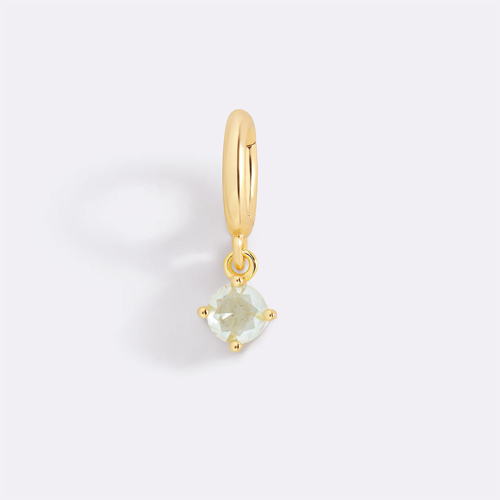Gold pendant with a clear gemstone on a light gray background