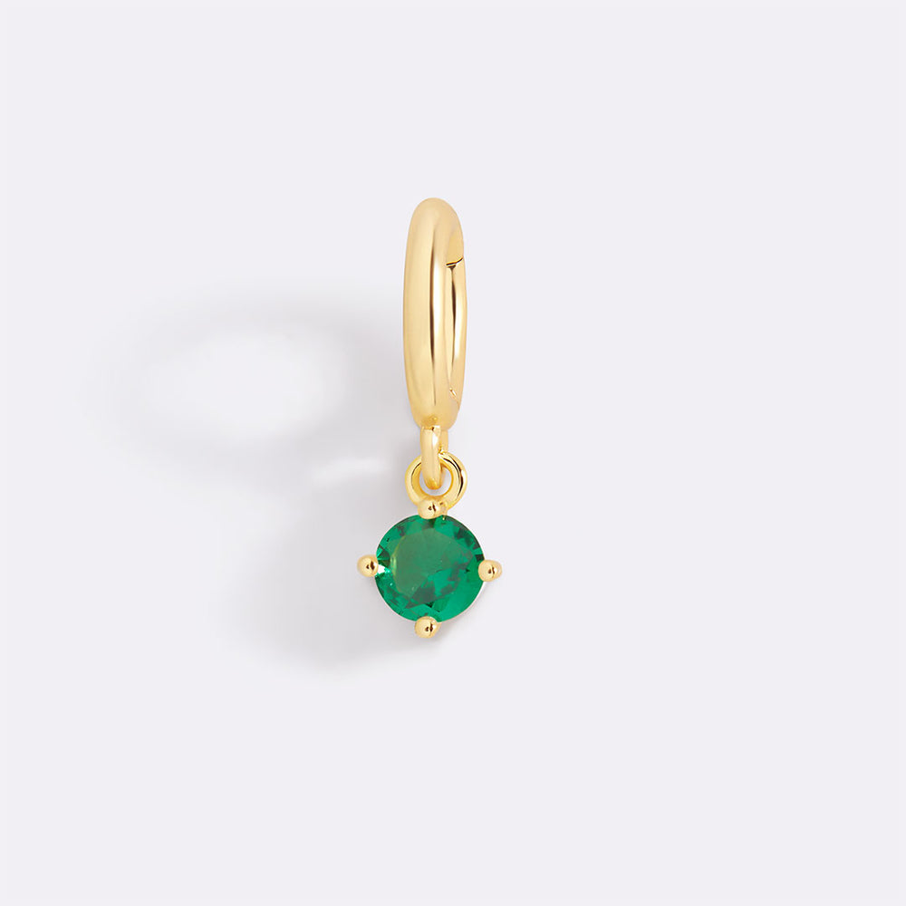 Gold earring with a green gemstone on a light gray background