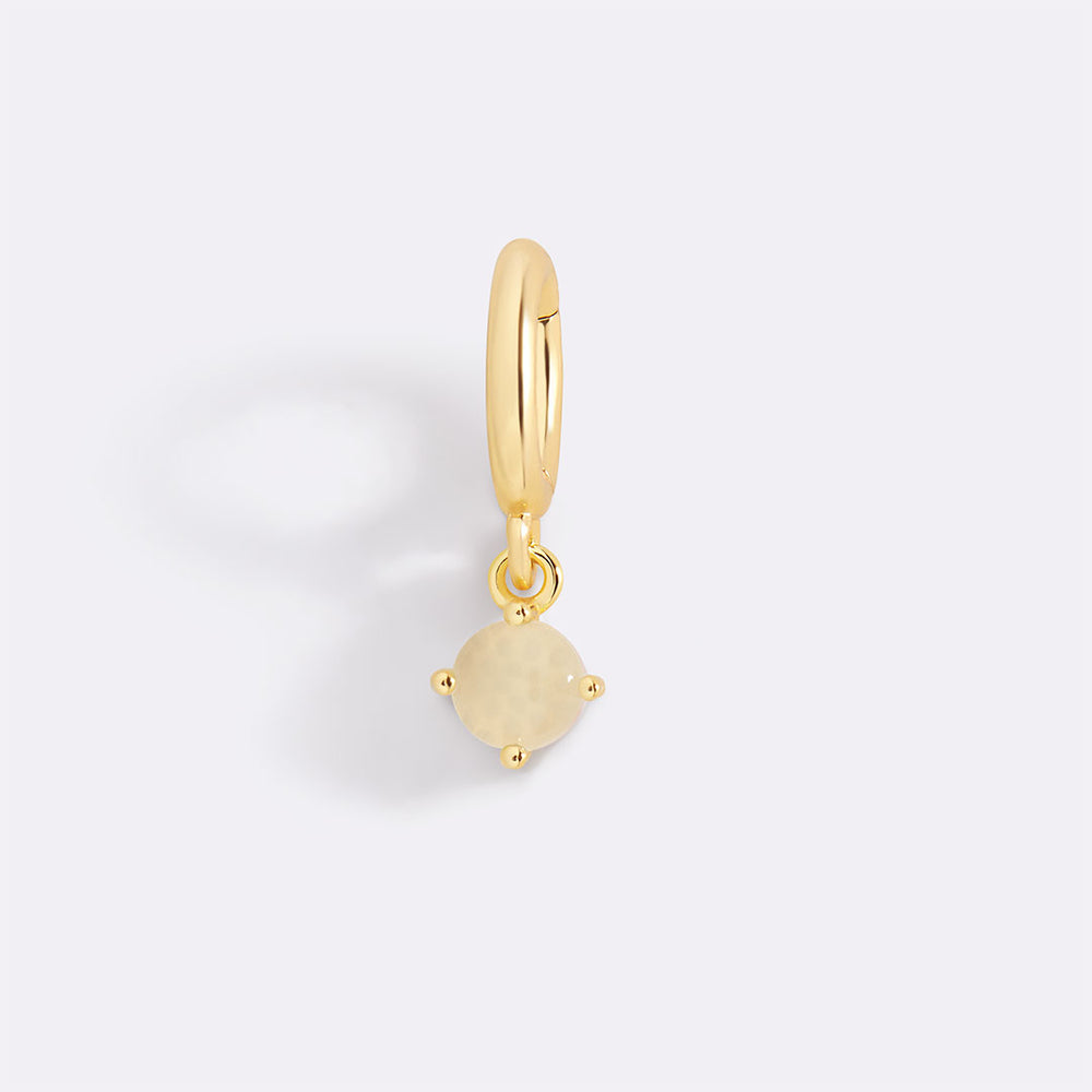 Gold pendant with a yellow gemstone on a light gray background