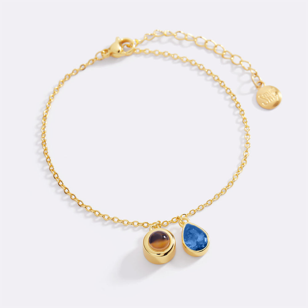 Gold bracelet with three gemstones on a light background