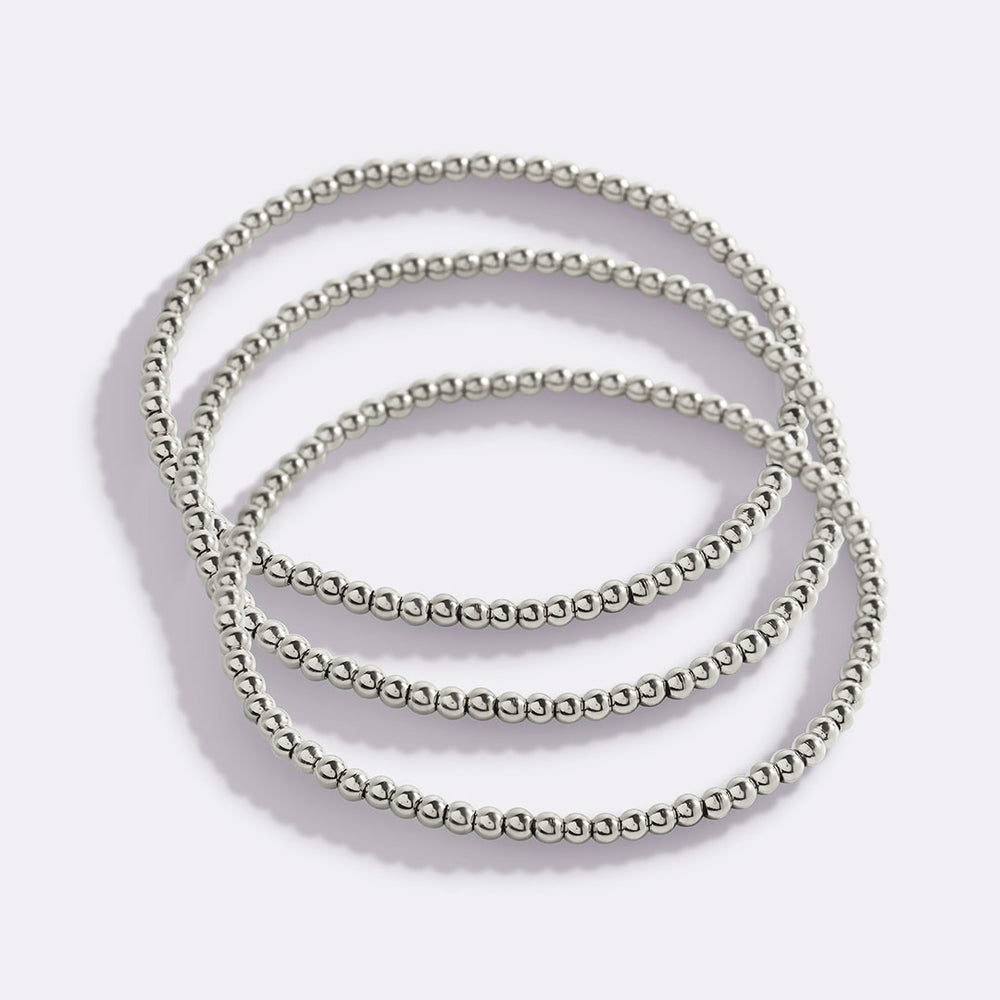 Set of silver beaded bracelets on a light gray background