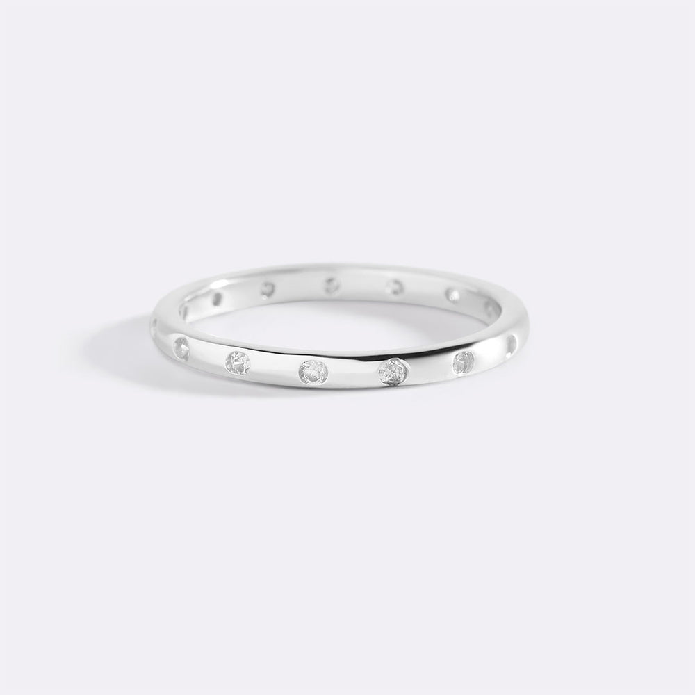 Silver ring with small diamonds on a light gray background