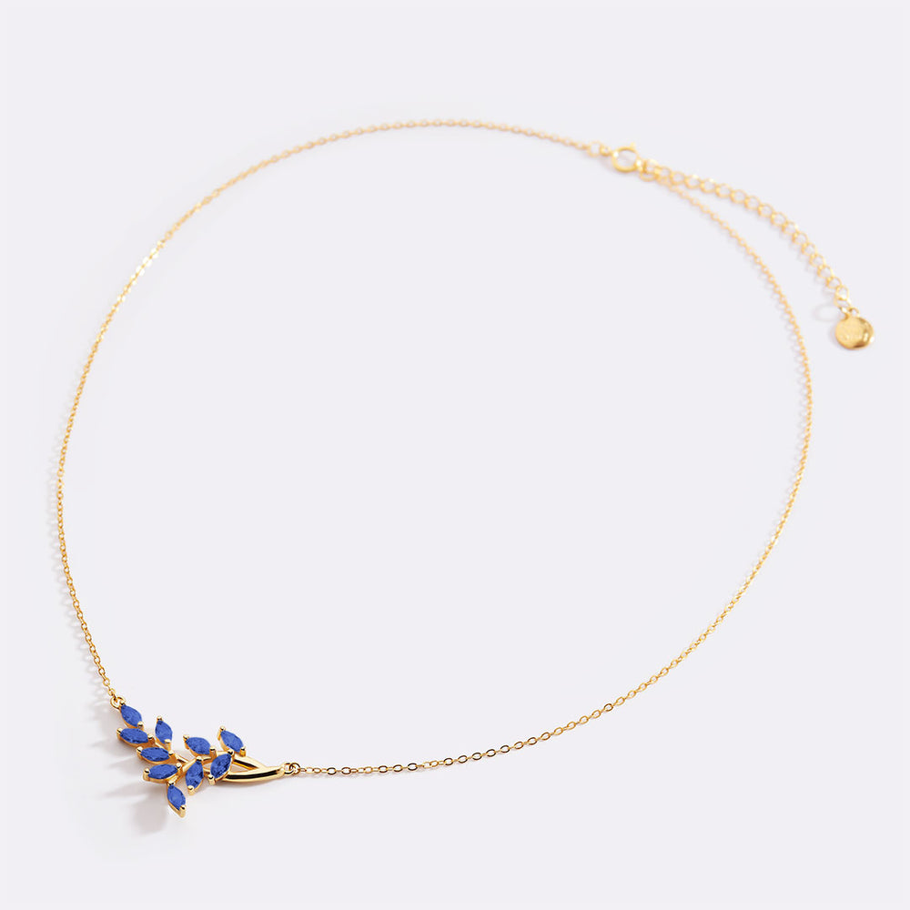 Gold necklace with blue gemstones on a light gray background