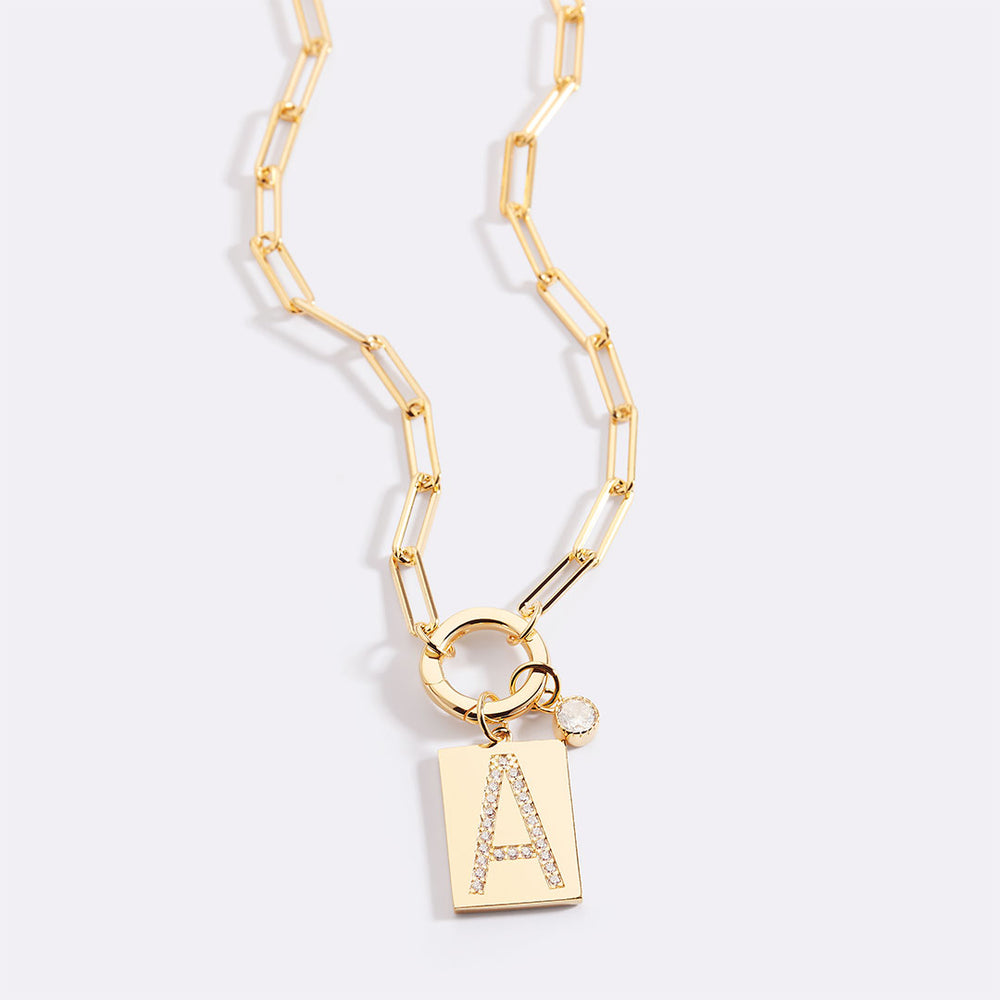 Gold necklace with a pendant featuring the letter 'A' on a light gray background
