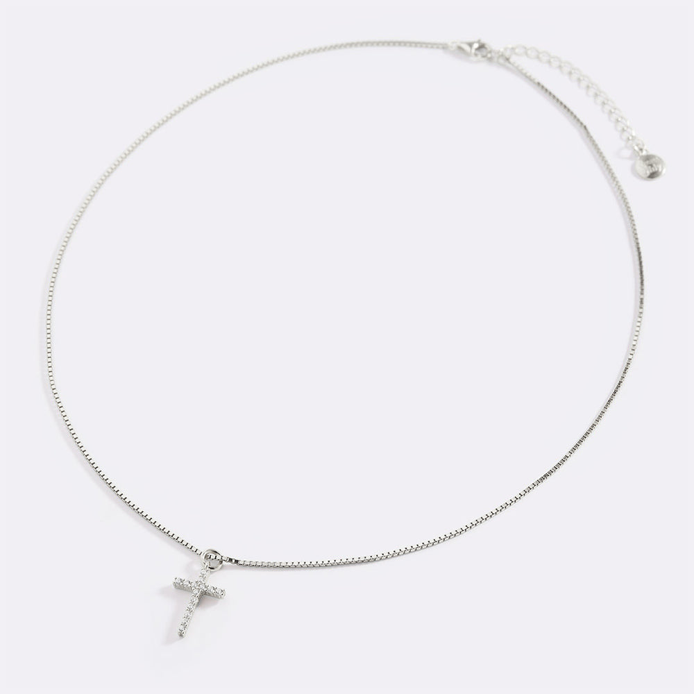 Silver necklace with a cross pendant on a light gray background