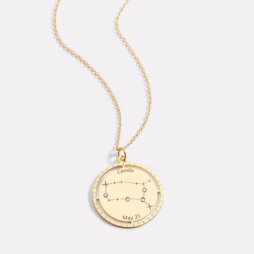 Gold necklace with a circular pendant featuring star constellations on a white background