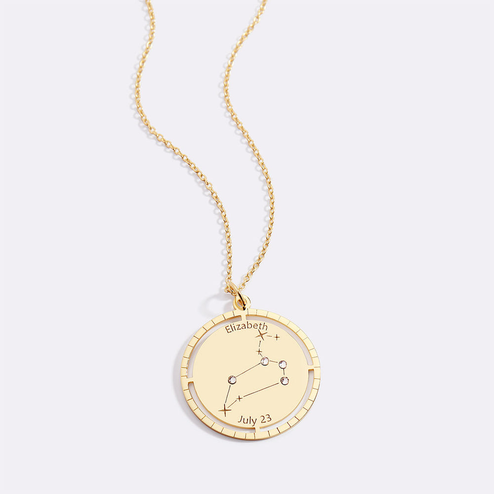 Gold necklace with a circular pendant featuring star constellations and engraved text on a white background