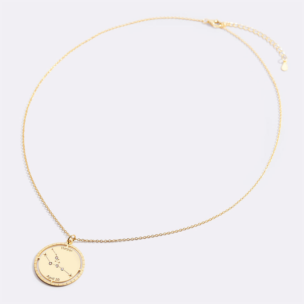 Gold necklace with a round pendant on a light gray background