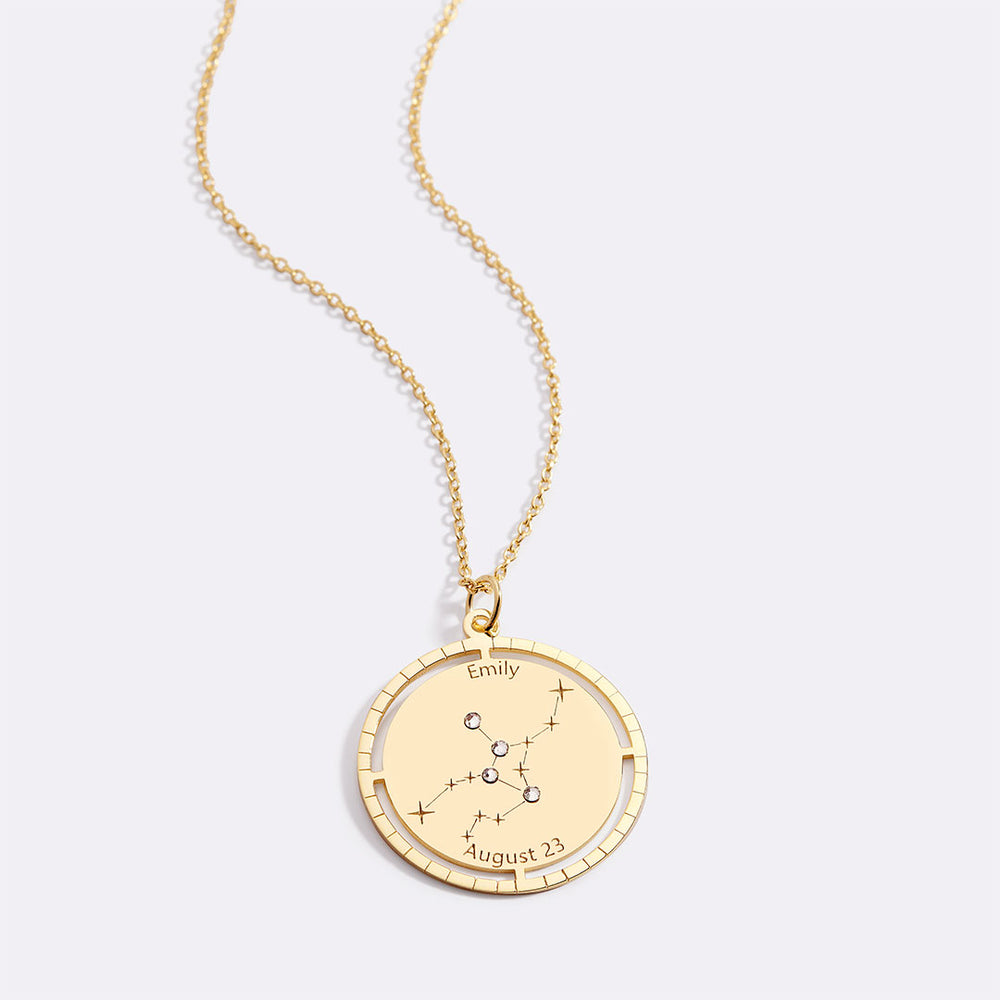 Gold necklace with a pendant featuring a constellation design on a light gray background