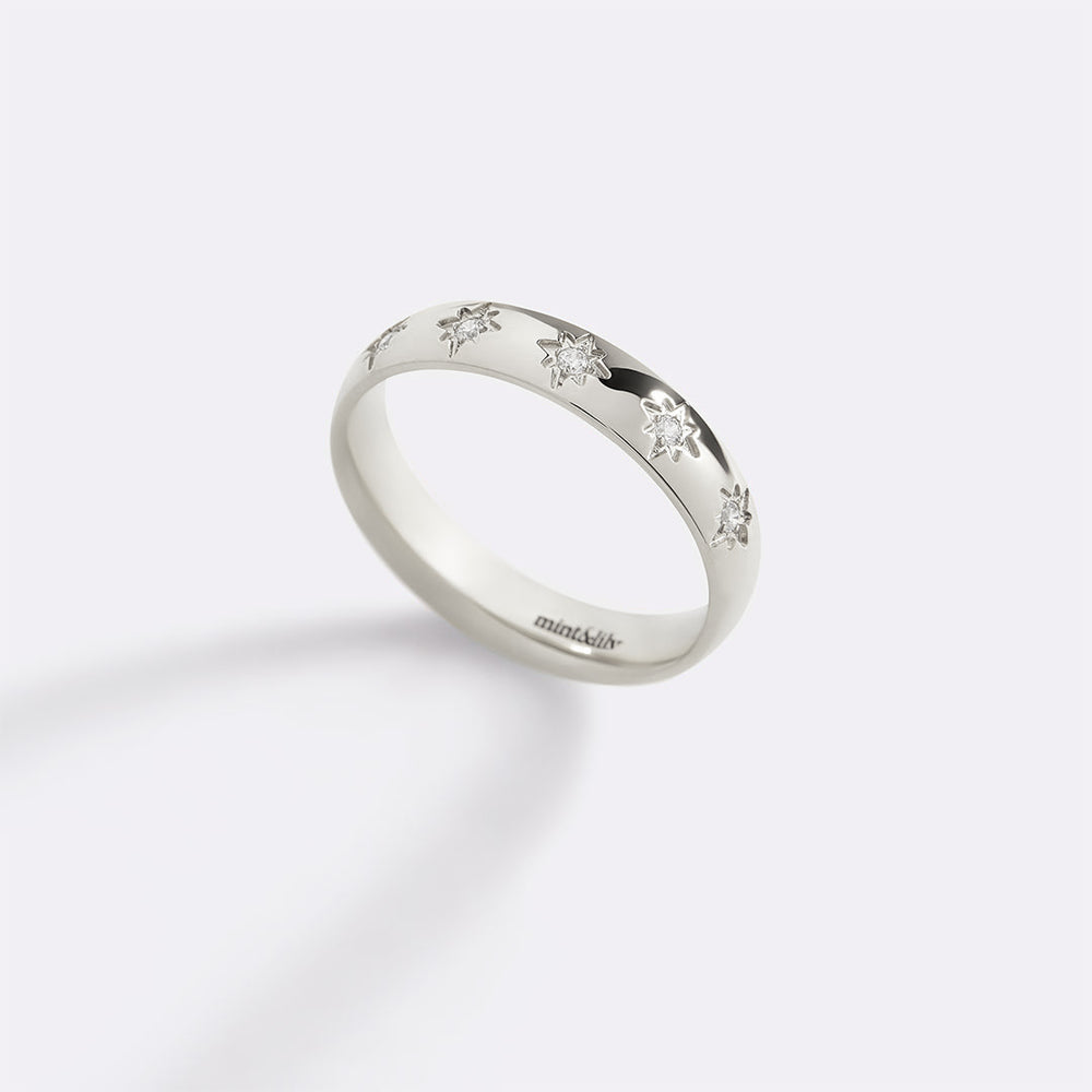 Silver ring with small diamonds on a light gray background