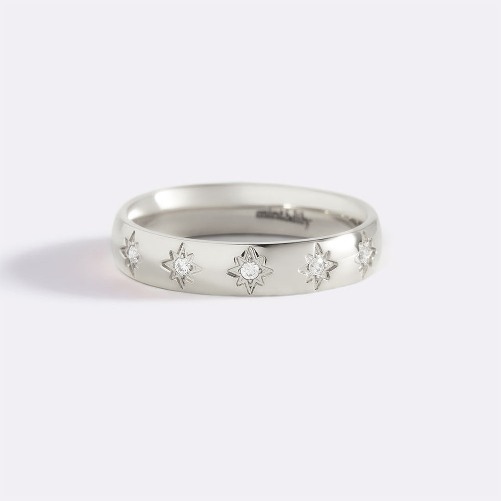 Silver ring with star-shaped diamond cutouts on a light gray background