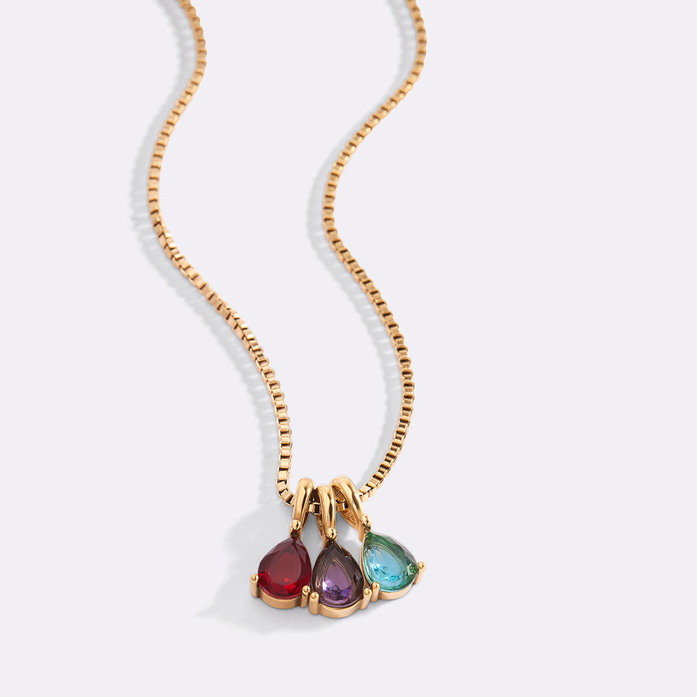 Gold necklace with three teardrop-shaped gemstones on a white background