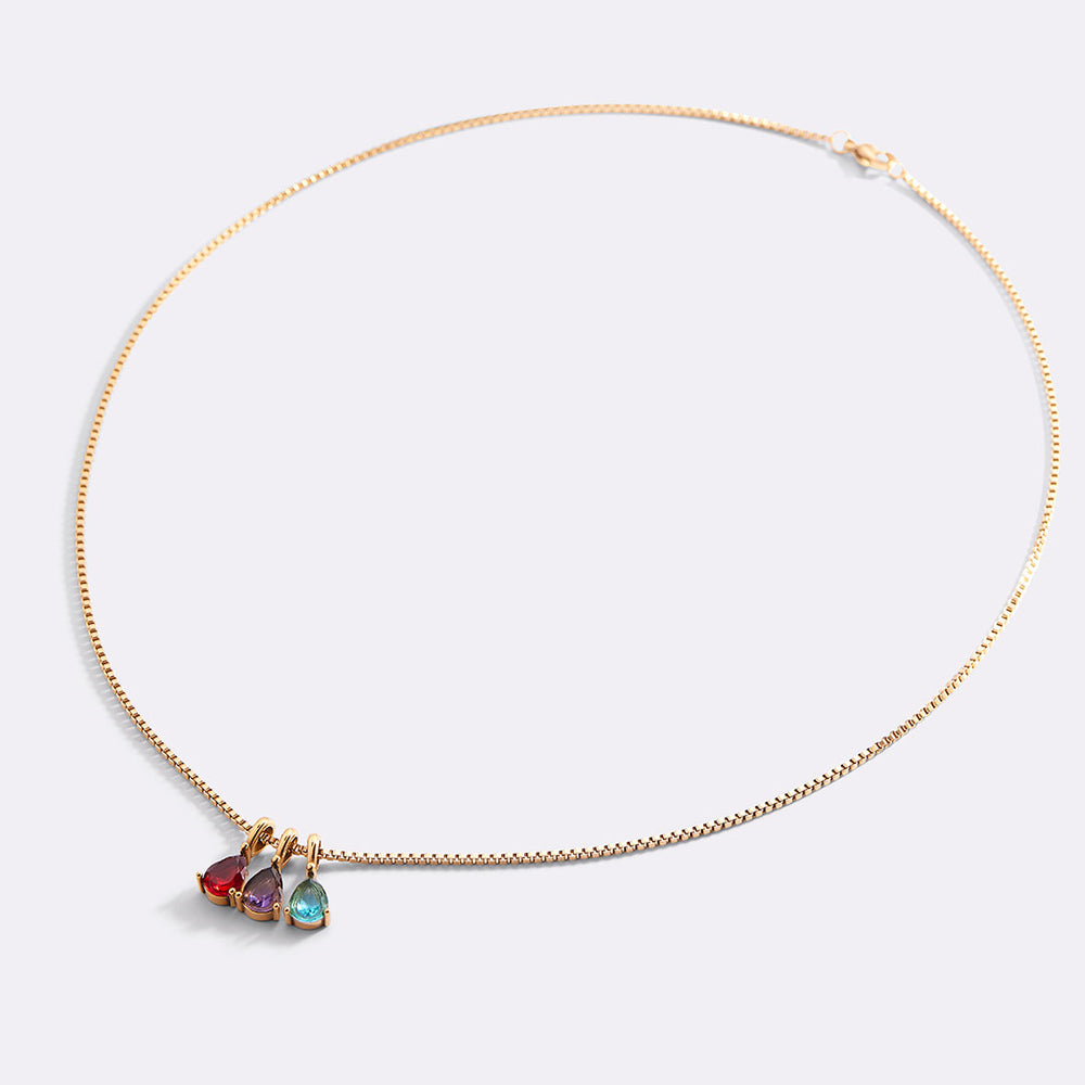 Gold necklace with three colorful gemstones on a light gray background