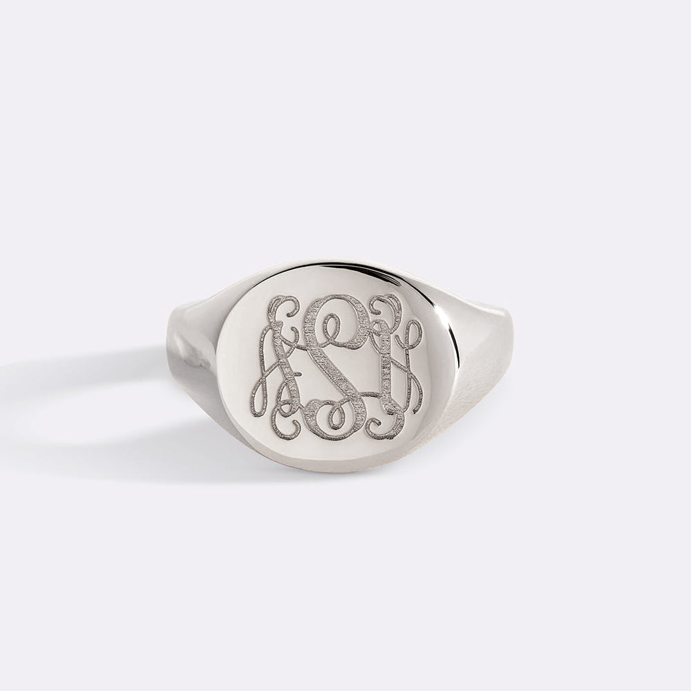 Silver signet ring with engraved monogram on a light gray background