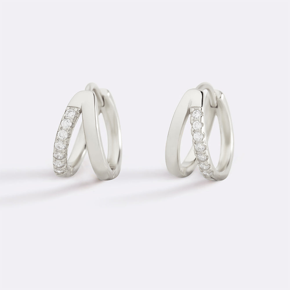 Pair of silver hoop earrings with embedded stones on a white background