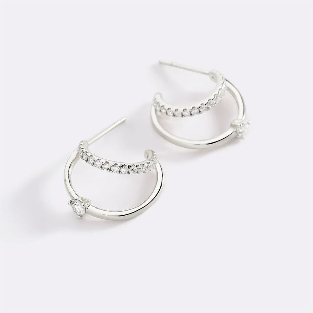 Silver hoop earrings with embedded stones on a light gray background
