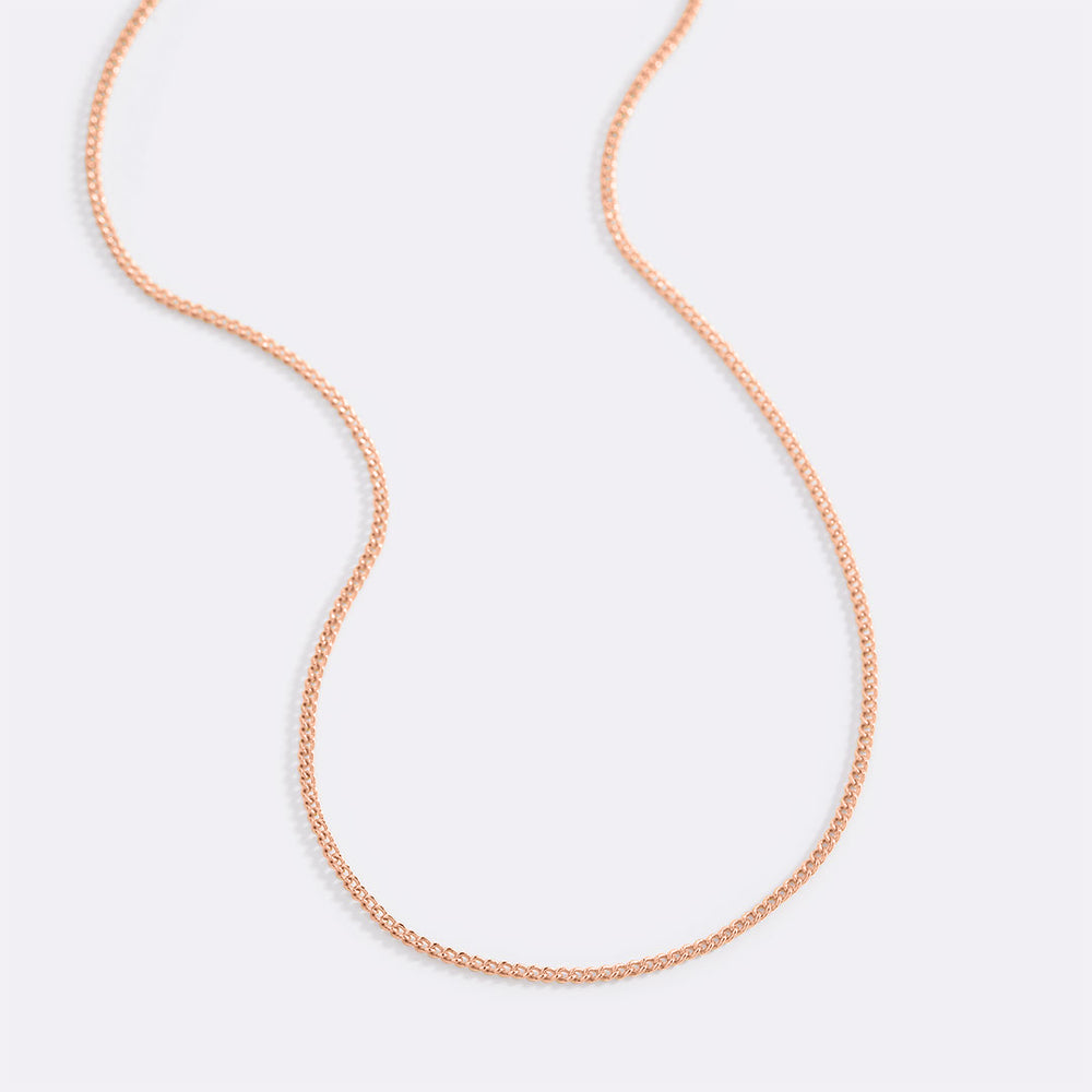 Rose gold chain necklace on a light gray background