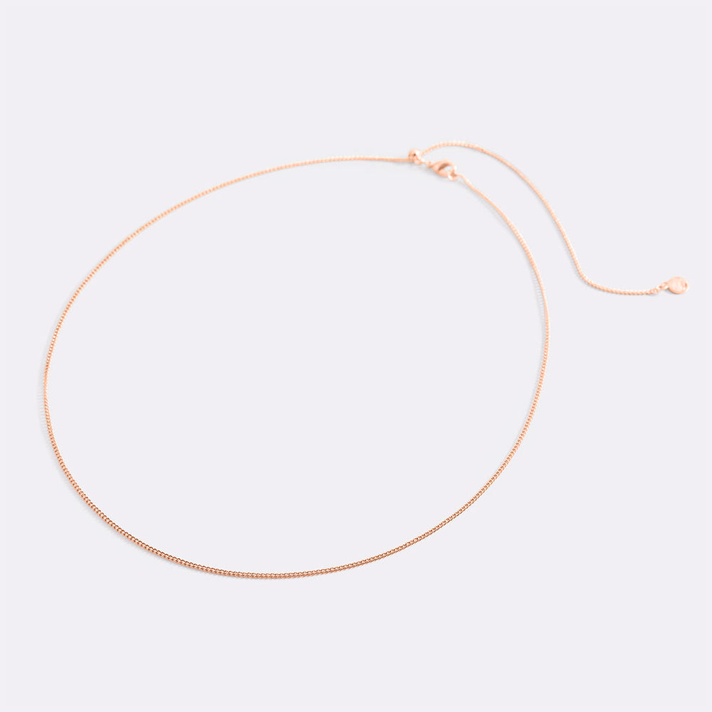 Rose gold necklace on a light pink background