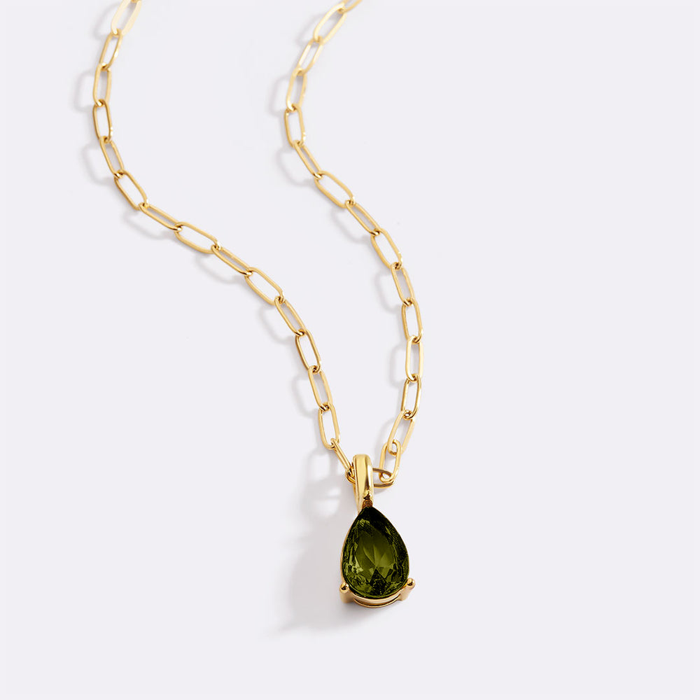 Gold necklace with a green teardrop pendant on a white background
