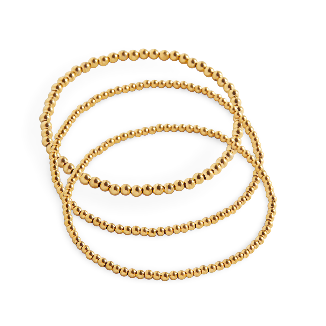 A set of gold-colored beaded bracelets stacked together.
