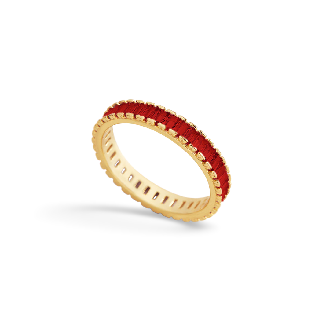 Gold ring with red gemstone on a light gray background